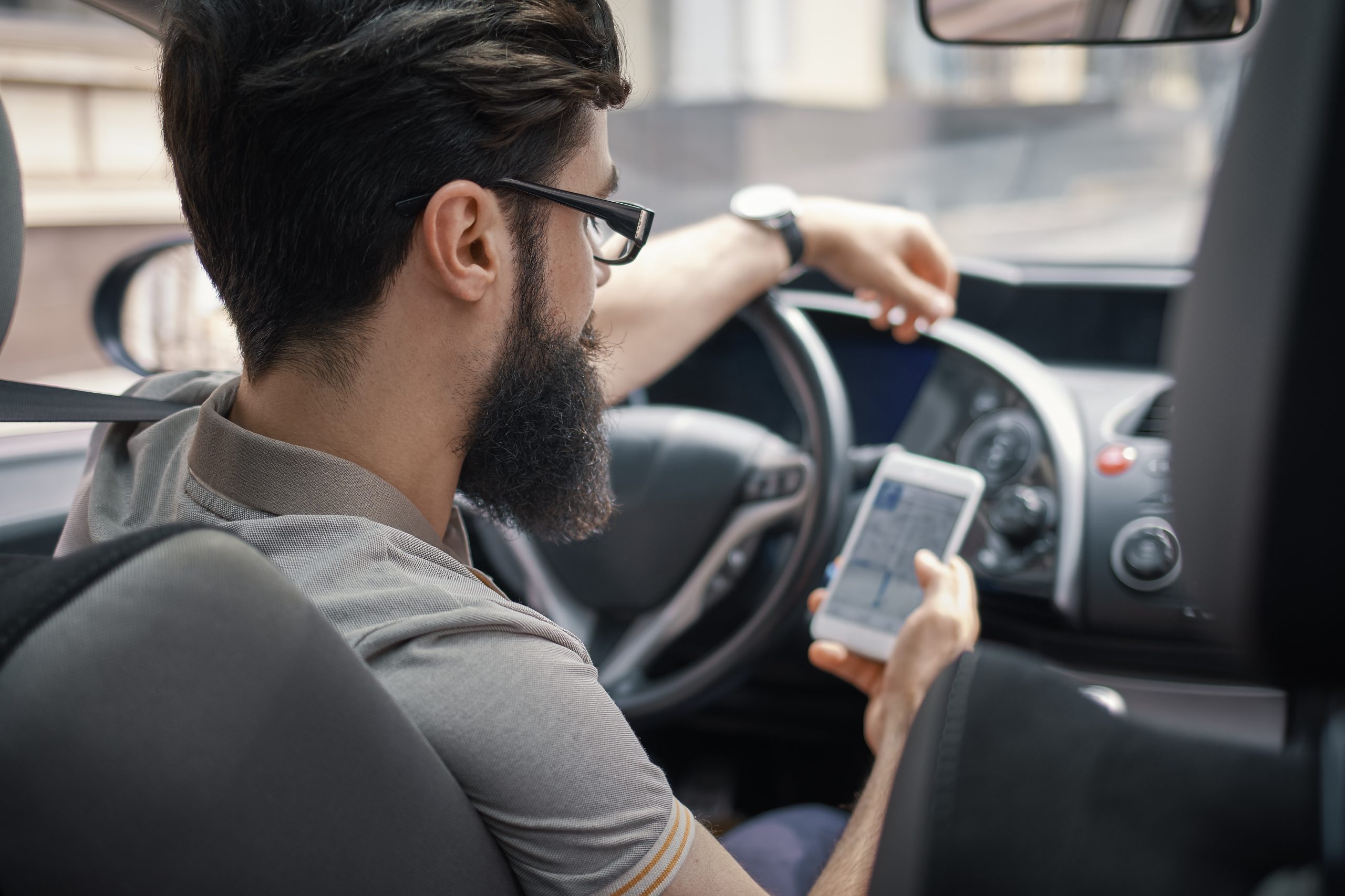 motorista de aplicativo sentado ao volante olha seu celular